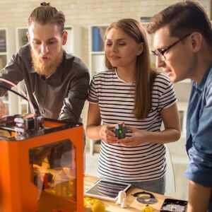 Drei Personen arbeiten an einem 3D-Drucker